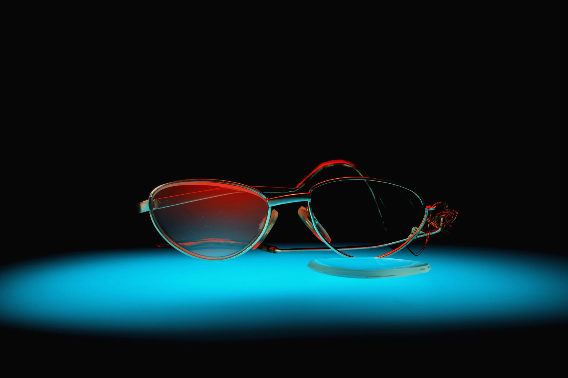 Broken glasses sit on a blue-lit surface.