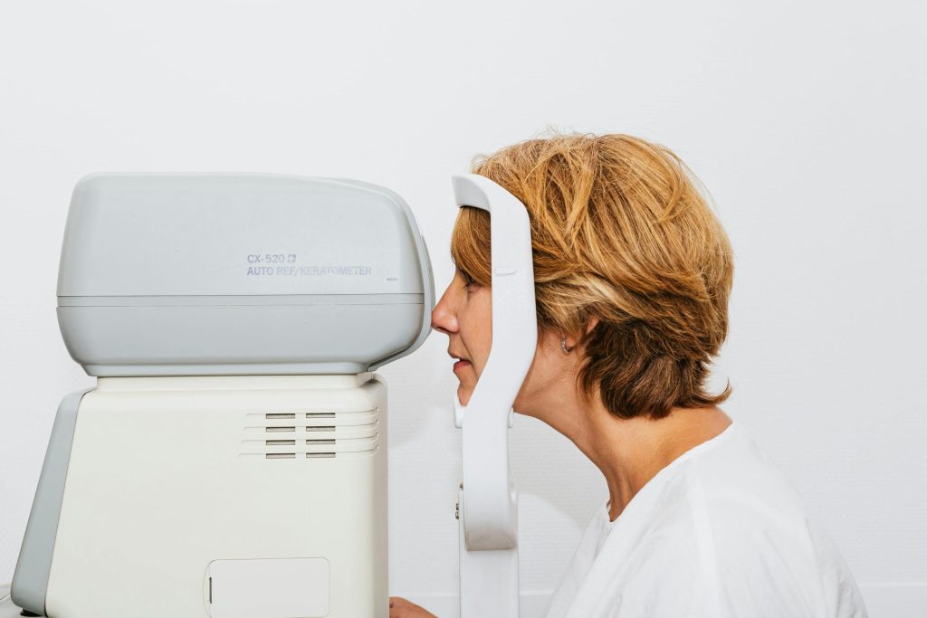 A woman undergoing an eye exam with an autorefractor in a clinical setting.
